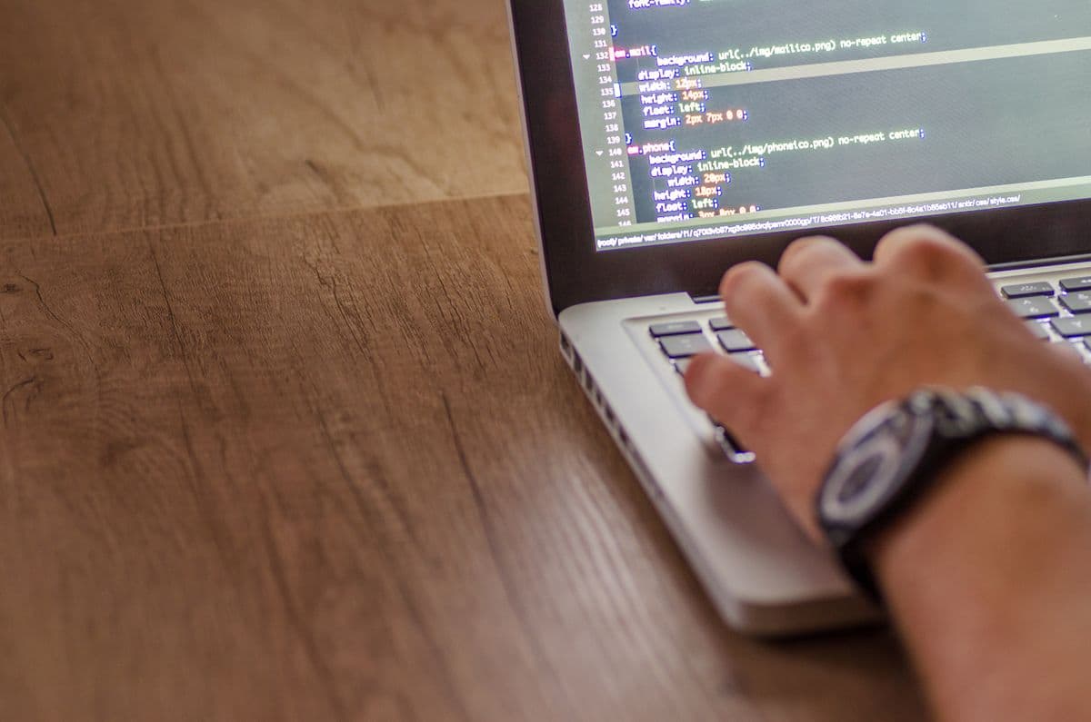 Hands typing website code on a laptop